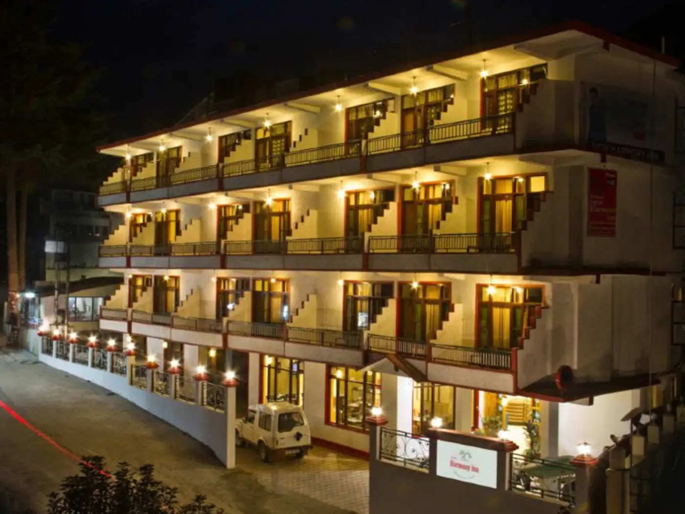 Hotel exterior at night with balconies and warm lighting. 