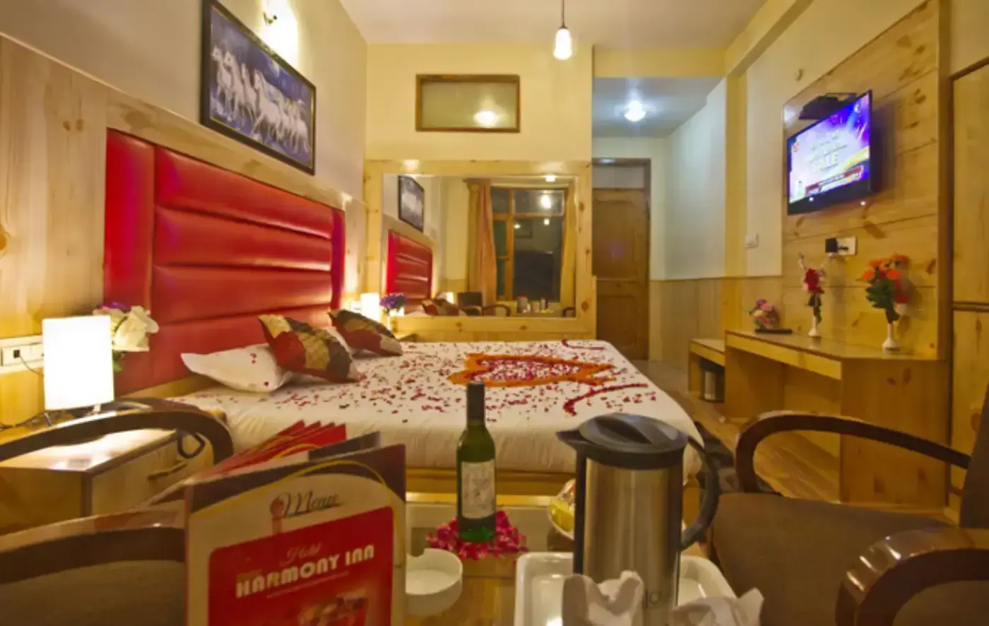 Romantic hotel room with rose petals on bed, wine, and menu