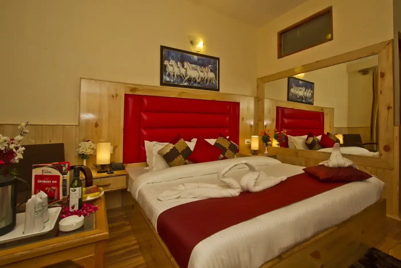 Romantic hotel room with rose petals on bed, wine